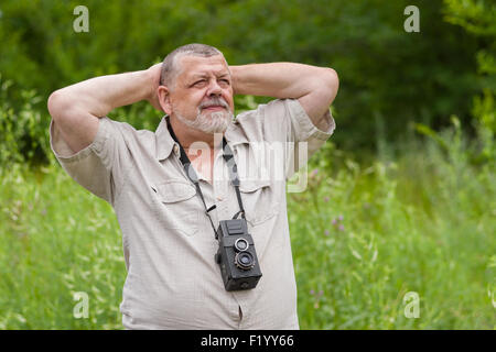 Outdoor portrait of a bearded senior man looking above and being happy Stock Photo