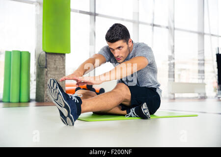 Portrait of a fitness man doing stretching exercises at gym Stock Photo