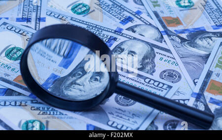 Hundred dollar banknotes under magnifying glass Stock Photo