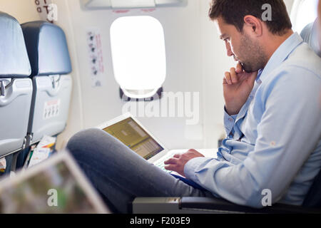 Businessman working with laptop on airplane. Stock Photo