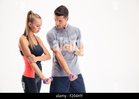 Portrait of a male trainer teaching woman how to working with dumbbells isolated on a white background Stock Photo