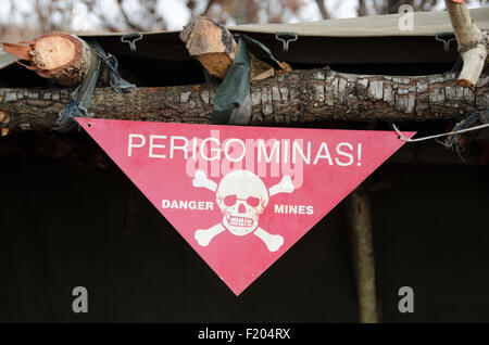 Angola, Danger sign warning of unexploded ordenence being stored in a small earth bunker for later safe disposal or detonation. Stock Photo