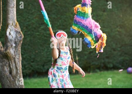 Girl playing pinata in garden Stock Photo