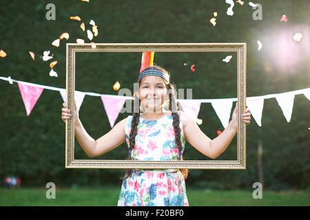 Portrait of girl looking through picture frame, smiling at camera Stock Photo