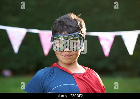 Portrait of boy wearing goggles and cape, looking at camera