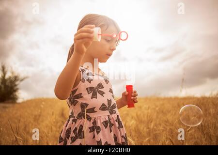 Girl blowing bubbles in wheat field Stock Photo