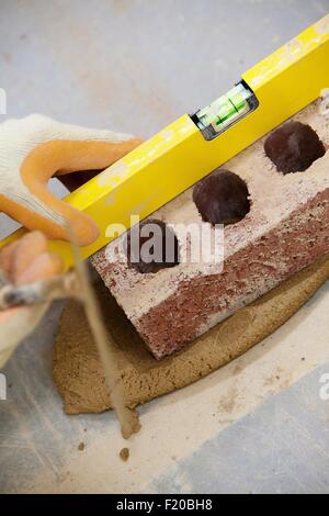 Close up of bricklayers hands using spirit level on brick Stock Photo