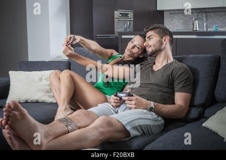 Young couple on sofa taking smartphone selfie Stock Photo