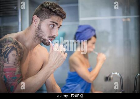 Young couple brushing teeth in bathroom Stock Photo
