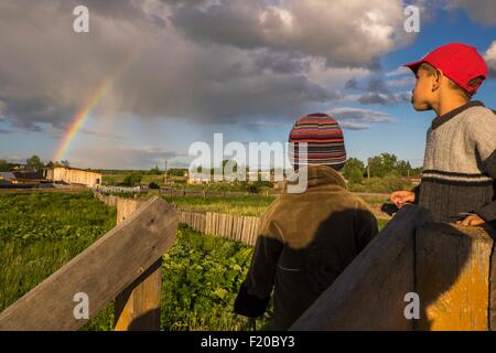 Two brothers gazing at rainbow from field Stock Photo