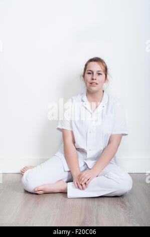 Portrait of young nurse sitting on floor Stock Photo