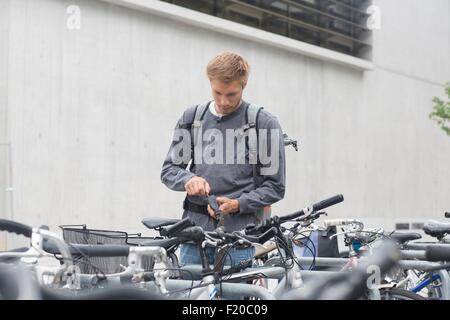 Mid adult using key to lock, unlock bicycle lock, looking down Stock Photo