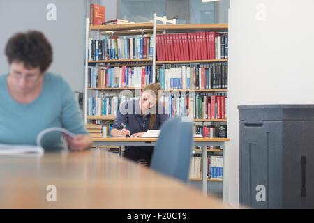 Female students reading textbooks at library desks Stock Photo