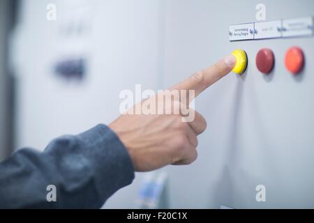 Hand of male technician pressing yellow button on control panel Stock Photo