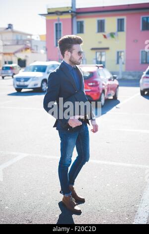 Young man carrying briefcase walking across parking lot Stock Photo