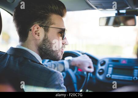 Rear view of young businessman driving car Stock Photo