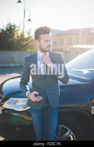 Young businessman adjusting tie in car park Stock Photo