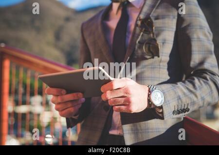 Cropped close up of young man using digital tablet on footbridge Stock Photo