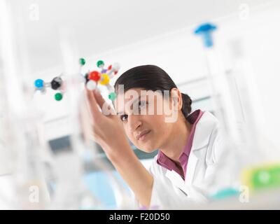 Female scientist in laboratory, viewing molecular model of a chemical formula Stock Photo
