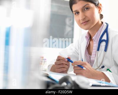 Portrait of female doctor at desk working on medical records Stock Photo