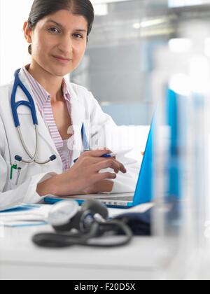 Portrait of female doctor at desk working on laptop