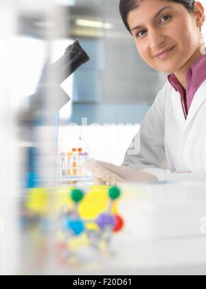 Portrait of female scientist testing blood sample using microscope Stock Photo