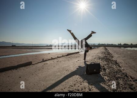 Mid adult businessman doing handstand on beach Stock Photo