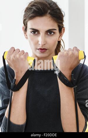 Close up of young woman exercising with resistance bands in living room Stock Photo