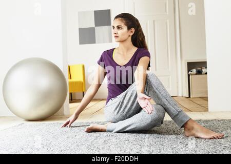 Young woman practicing yoga on living room floor Stock Photo