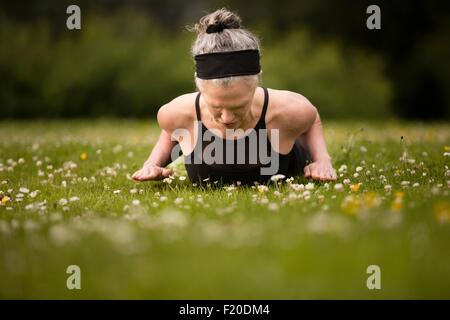 Mature woman practicing yoga cobra pose in field Stock Photo