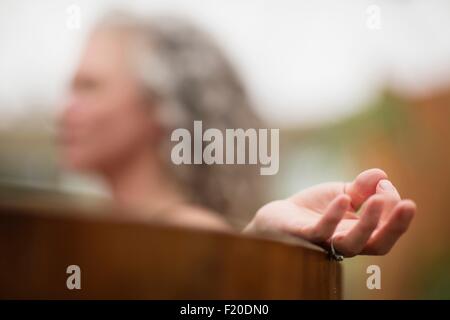 Hand of mature woman meditating in hot tub at eco retreat Stock Photo