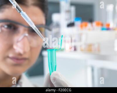Female scientist pippetting sample into eppendorf tube for analysis in laboratory Stock Photo