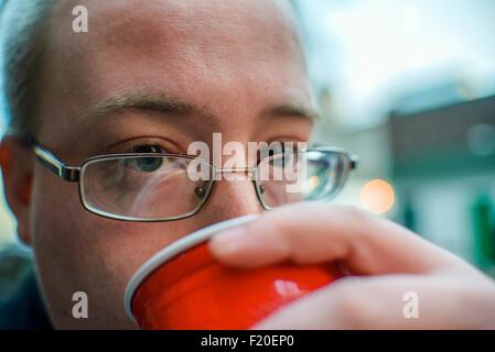 Portrait of young man drinking from takeaway cup on street Stock Photo