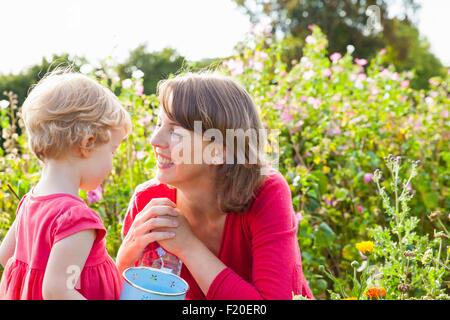 Mid adult mother and toddler daughter in flower field Stock Photo
