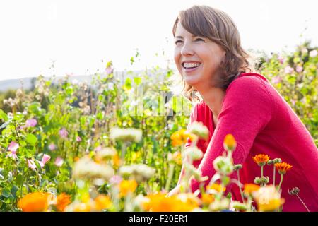Mid adult woman crouching in flower field Stock Photo