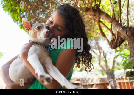 Portrait of girl in garden hugging dog Stock Photo