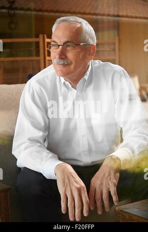 Senior man at home, sitting in chair, looking away Stock Photo