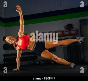 Young woman doing side push up in gym Stock Photo