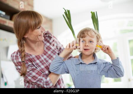 Mother and son playing with vegetable in kitchen Stock Photo