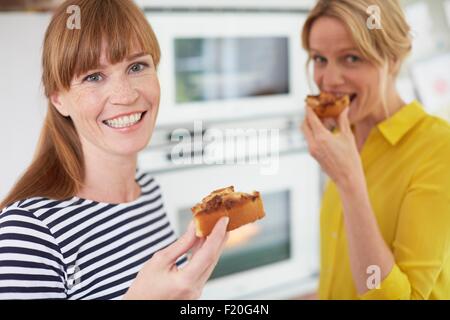 Women eating cake in kitchen Stock Photo