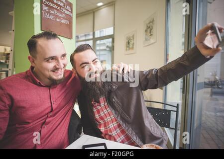 Gay couple taking selfie in cafe Stock Photo