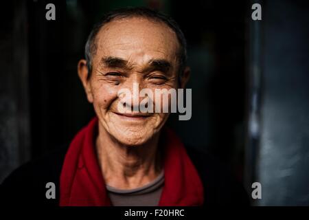 Portrait of senior man wearing red scarf around neck looking at camera smiling Stock Photo