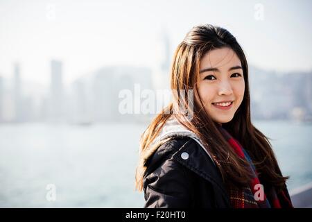 Portrait of young woman wearing checked scarf and leather jacket, looking at camera Stock Photo