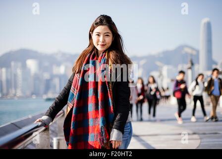 Portrait of young woman wearing checked scarf and leather jacket, looking at camera Stock Photo