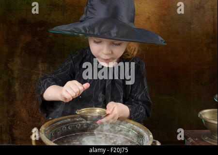 little halloween witch with cauldron in an ancient kitchen Stock Photo