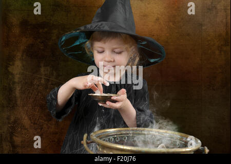 little halloween witch with cauldron in an ancient kitchen Stock Photo