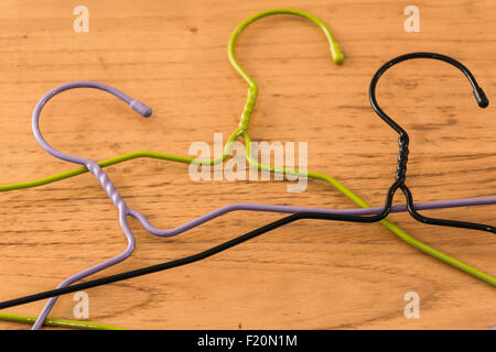 three colored hangers on a wooden table Stock Photo