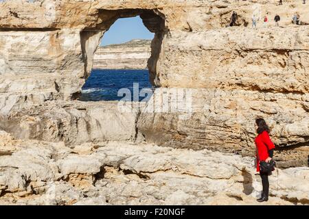 Malta, Gozo, Dwejra, Azure window, japanese tourist on rocks in front of a natural arch in the cliff by the sea Stock Photo