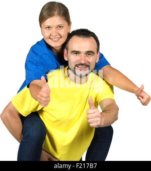 happy man wearing blue shirt  carrying young woman wearing yellow shirt, holding thumb up,looking at camera,  isolated over whit Stock Photo