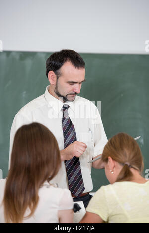 students in the auditorium listening teacher explanation backs to camera Stock Photo